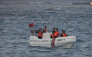 A boat with men floats in the China sea.