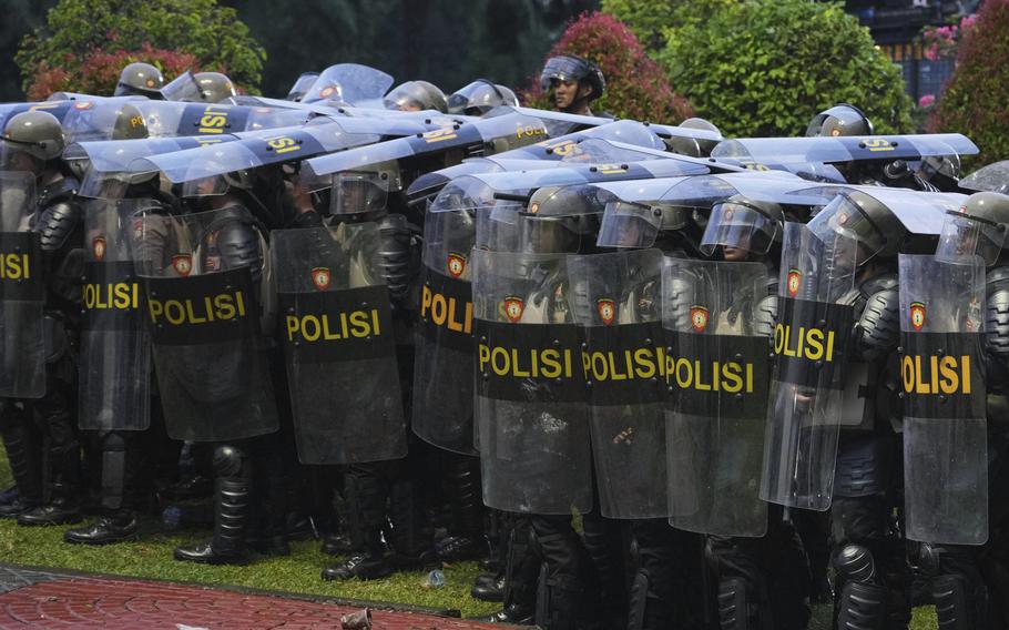 Police officers stand together while protestors rally in Jakarta, Indonesia.