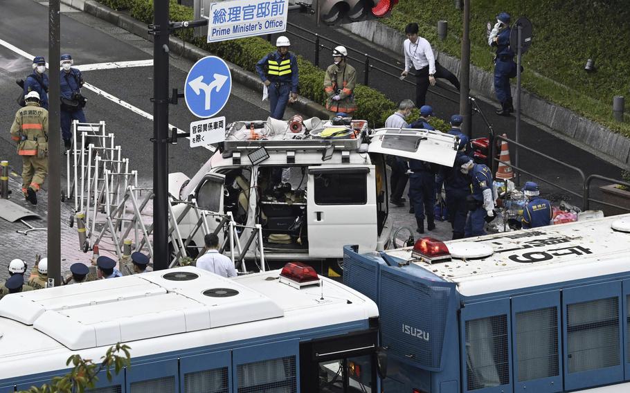 Officials work near a vehicle, center, which was stuck against a barricade near the prime minister's office in Tokyo Saturday, Oct. 19, 2024. 