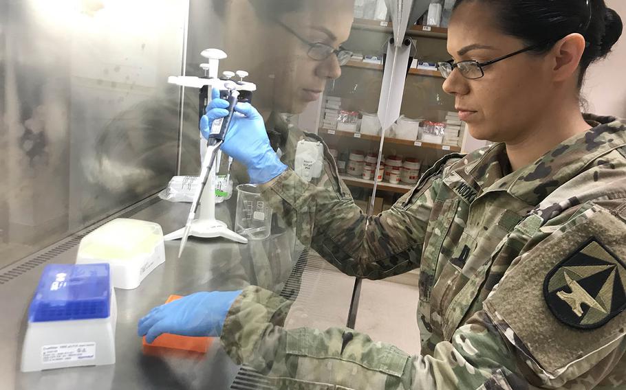 U.S. Army Capt. Jennifer Kooken is reflected in a glass screen that protects samples from contamination at the Australian Defence Force's Malaria and Infectious Disease Institute in Brisbane, Australia, Saturday, July 20, 2019.