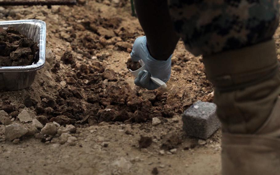 A Marine collect soil samples for Japanese officials, May 1, 2020, where firefighting foam leaked last month at Marine Corps Air Station Futenma, Okinawa.