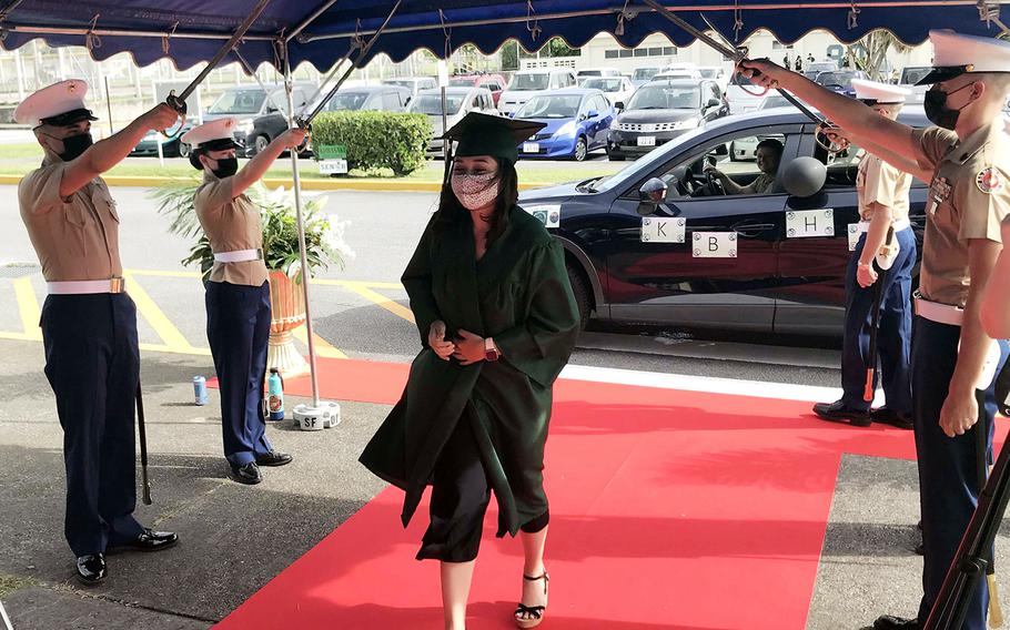 Kubasaki High School senior Tina Davis is saluted with a Marine sabre arch while accepting her diploma during a drive-thru ceremony at Camp Foster, Okinawa, Saturday, June 6, 2020.