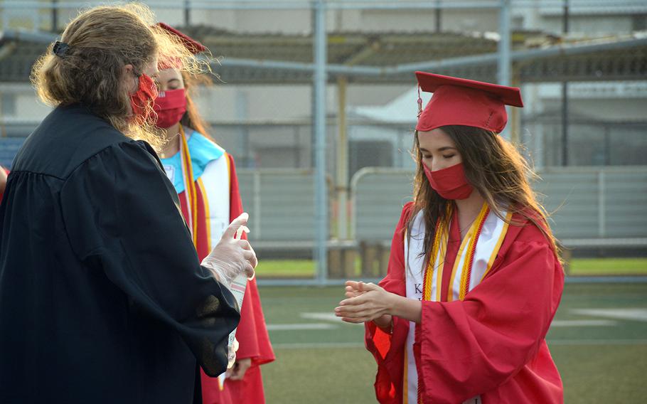 A Nile C. Kinnick High School senior uses hand sanitizer before approaching the stage to accept her diploma during a ceremony at Yokosuka Naval Base, Japan, Friday, June 5, 2020.