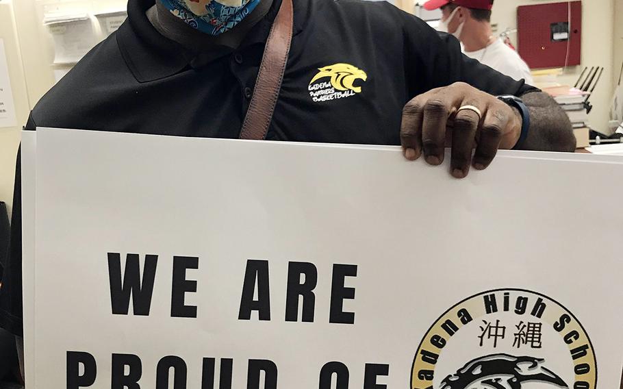 Kadena High School instructor Antiwon Tucker shows off a sign used during a drive-thru graduation ceremony at Kadena Air Base, Japan, Friday, June 5, 2020.