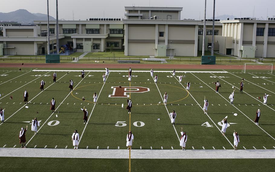 New graduates from Matthew C. Perry High School toss their caps into the air during a ceremony at Marine Corps Air Station Iwakuni, Japan, Thursday, June 4, 2020.