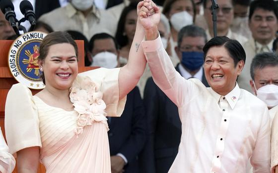 A man and a woman raise their hands during a ceremony.