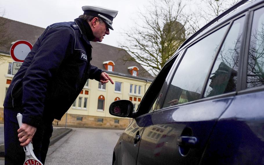 German police officer David Giesler instructs a motorist to pull into a parking lot for inspection during a random traffic check on the east side of Kaiserslautern, Germany, on Jan. 28, 2015.