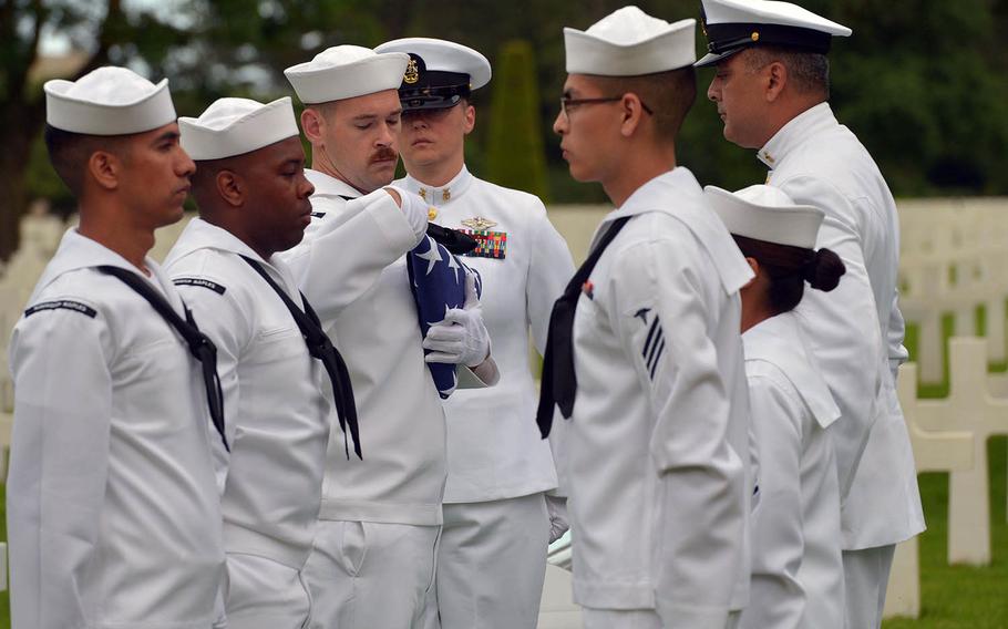 Sailors from the U.S. Naval Hospital Naples, Italy, finish folding the American flag during a memorial service for U.S. Naval Reserve Radioman 2nd Class Julius 