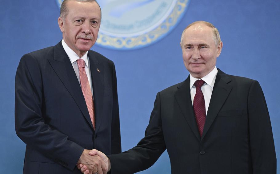 Russian President and Turkish President shake hands for photos.