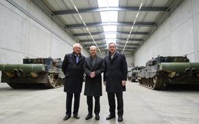 Armin Papperger, from left, CEO of Rheinmetall, German Chancellor Olaf Scholz and Boris Pistorius, German Minister of Defense, stand in a hall with Leopard 2A4 main battle tanks in Unterluess, Germany, Feb. 12, 2024. 