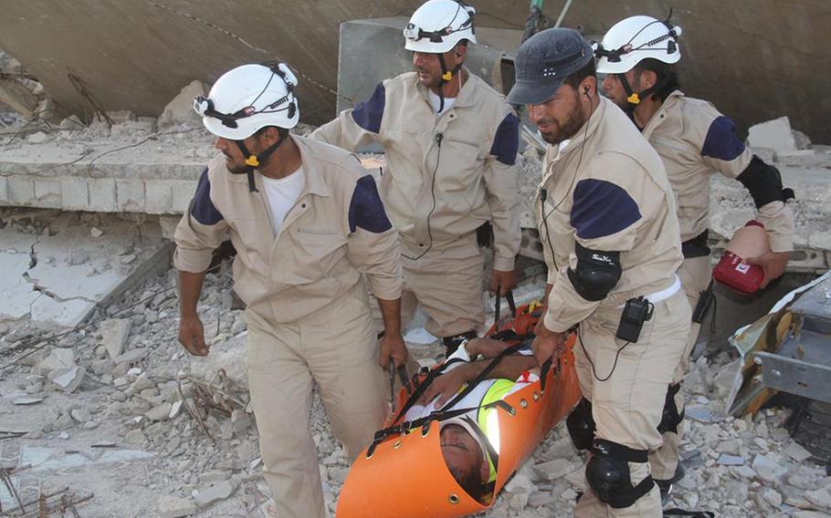 In this photo posted on August 21, 2014, provided by Civil Defense Idlib, a group of volunteers in northern Syria which has been authenticated based on its contents and other AP reporting, show Syrian civil defense workers with their white helmets, carry on of their comrade during a training session, in Idlib province, northern Syria. 
