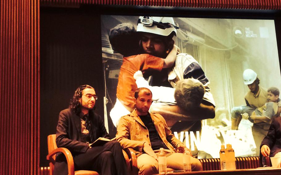 In this photo taken by a mobile phone on Wednesday Sept. 24, 2014, Read Saleh left, the head of the civil defense units in the northern city of Idlib, and Farouk al-Habib, right, a media campaigner for the rescuers known as the White Helmets, sit on a panel to draw attention to their work in Syria as world leaders come together for the annual UN general assembly meetings, in midtown New York. 