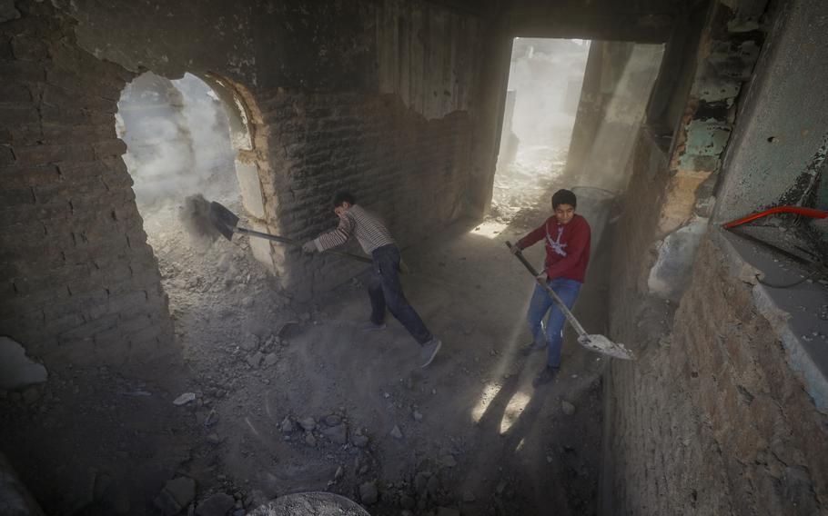 Two boys shovel rubble in Syria.