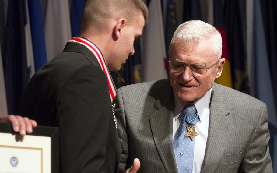 Medal of Honor recipient Wesley Fox shakes hands with Connor Stotts after presenting him with the Citizen Honors award during a ceremony at Arlington National Cemetery on Medal of Honor Day, March 25, 2014.