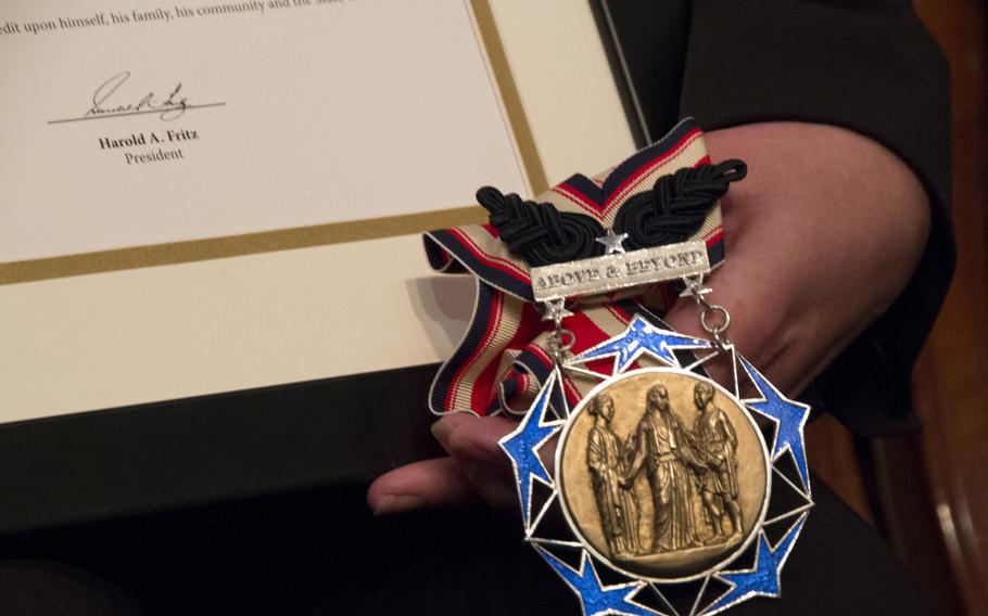 Sharon Landsberry displays the Citizen Honors award she accepted on behalf of her late husband, Michael, during a eremony at Arlington National Cemetery on Medal of Honor Day, March 25, 2014.