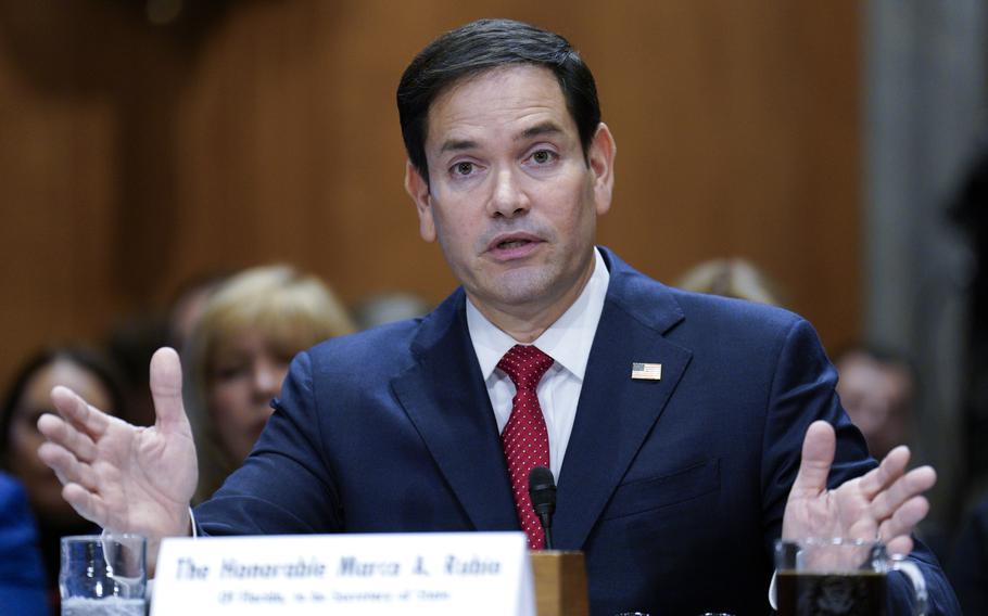 Marco Rubio gestures with his hands while seated at a table during a congressional hearing.