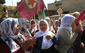 Kurdish women, one waving a flag of the outlawed Kurdish rebel group, the PKK, applaud while lining the road, as the convoy carrying the body of U.S. citizen Keith Broomfield, killed in fighting with the militants of the Islamic State group in Kobani, Syria, is driven by through Suruc, on the Turkey-Syria border, Thursday, June 11, 2015. Broomfield, 20 from Massachusetts, died June 3 in battle in a Syrian village near Kobani, making him likely the first U.S. citizen to die fighting alongside Kurds against the Islamic State group.  (AP Photo/Lefteris Pitarakis)