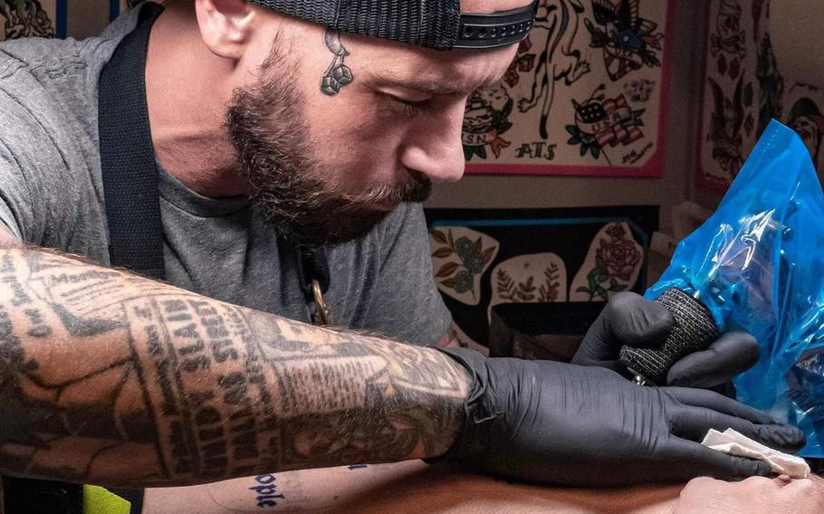 A tattoo artist works on a tattoo on the arm of a customer Stock Photo -  Alamy