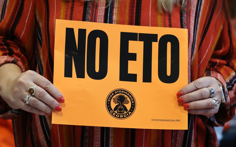 Jenni Shover holds a protest sign while Cobb County officials and environmental regulators hold a town hall and community forum about ethylene oxide emissions near Smyrna, Georgia. 