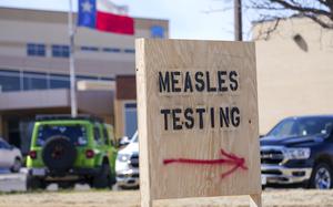 A sign says measles testing with an arrow toward the site.