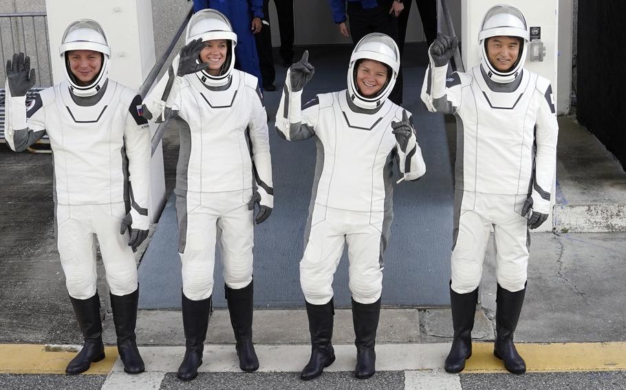 Astronauts wave before leaving a building in Florida.