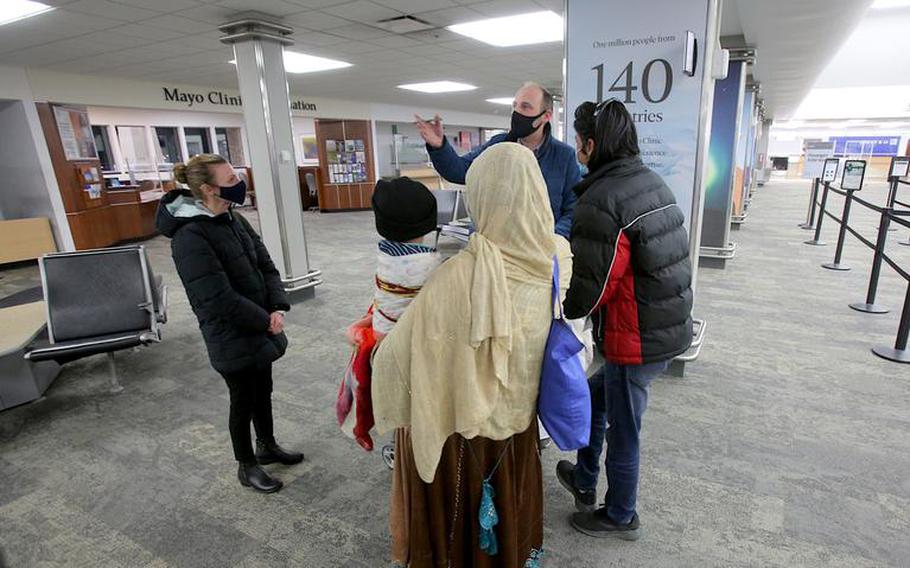 John Meyers, Catholic Charities director of refugee resettlement, top, and Kristina Hammell, left, greet a family of arrivals from Afghanistan at the Rochester International Airport Tuesday, Nov. 2, 2021. 