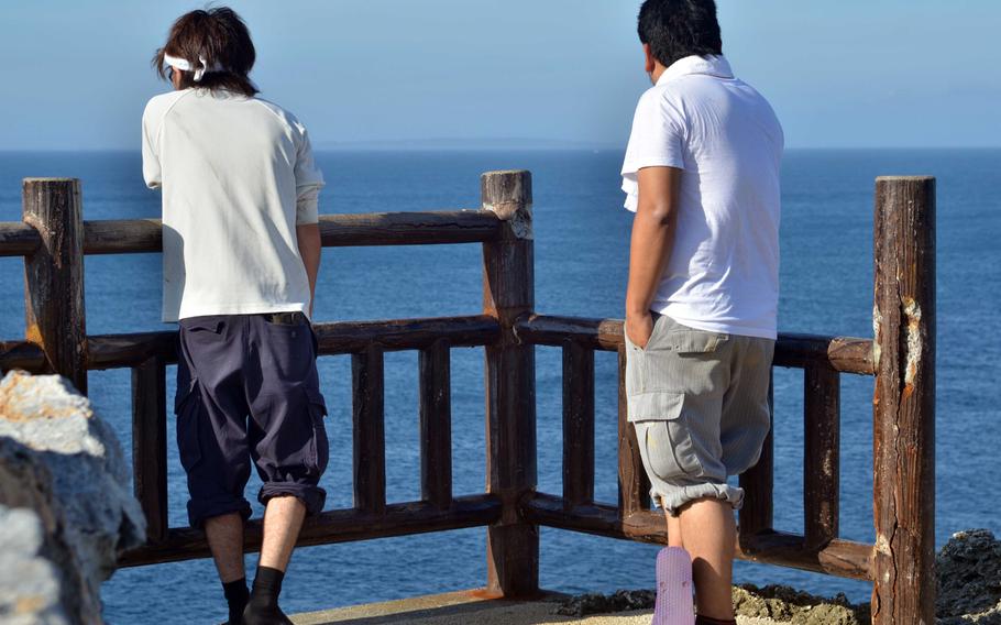 What most folk come to Cape Hedo for: to stand at the northernmost point on Okinawa. Two tourists gaze at the waters of the East China Sea, with Yoron Island 20 miles north visible througjh haze.