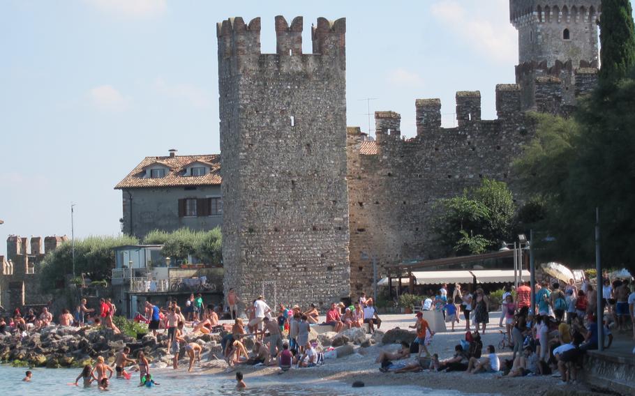 Lake Garda laps at the Sirmione shore decorated by old stone walls and turrets.