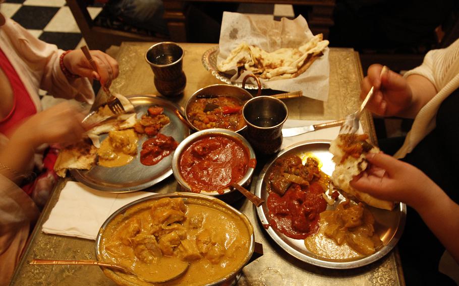 Dishes from front to back at Cafe Maharani: chiucken shahi korma, lamb roghan josh, vegetable jalfrezi masala, and naan. 